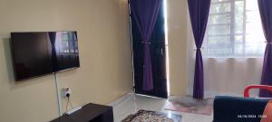 a living room with a tv and purple curtains at Mwango Deluxe Apartments in Voi
