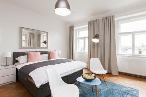 a bedroom with a large bed and two white chairs at Prague Center Apartments in Prague