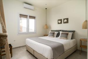 a white bedroom with a large bed and a window at EuGeniaS Villa in Agios Gordios