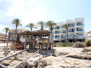 a building on the beach with palm trees in the background at Espardell nº4 in Es Pujols +4 photos