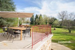 un tavolo in legno con sedie e un ombrellone su una terrazza di Maison Léonce Blanc - Prestige in Lubersac a Lubersac