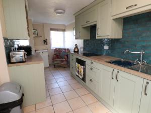 a kitchen with white cabinets and a sink at 11 Penygroes in Llantrisant