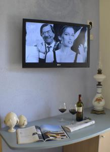 a television on a wall with a table with wine glasses at Masseria Asciano in Ostuni