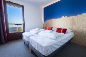 Un dormitorio con una cama grande con una ventana grande. en Côté Lac Hostel Evian, en Évian-les-Bains