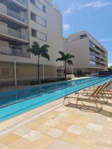 ein Swimmingpool mit Stühlen und einem Gebäude in der Unterkunft L23 apartamento alto padrão-Itagua in Ubatuba