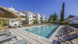 a swimming pool with lounge chairs and a hotel at Jardins do Golfe at Vale do Lobo in Vale do Lobo