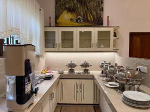 a kitchen with white cabinets and a counter with dishes at Water Pearl in Kosgama
