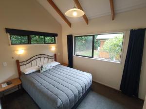 a bedroom with a large bed and two windows at Kerigold Secluded Chalets Motel in Kerikeri
