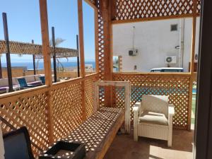 Dahab Hills Villa Resort في دهب: شرفة مع مقعد وإطلالة على الشاطئ