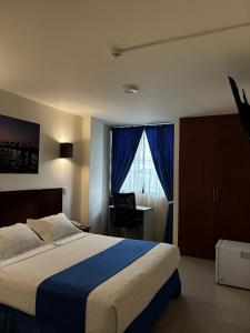 a bedroom with a large bed and a window at Hotel Puertoventura in Machala +4 photos
