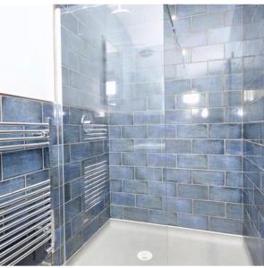 a blue tiled bathroom with a glass shower at Bumble cottage in Albrighton +6 photos
