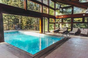 an indoor swimming pool in a house with windows at Arbolar, Casas de Montaña- Piscina climatizada in Villa La Angostura