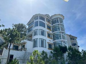 ein weißes Gebäude mit Bäumen davor in der Unterkunft Rocosy Villa DaLat in Khu Chi Lăng