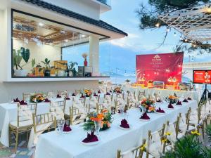 einen langen Tisch mit weißen Tischen und Stühlen in der Unterkunft Rocosy Villa DaLat in Khu Chi Lăng