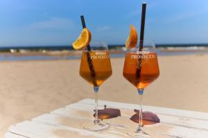 two wine glasses sitting on a table at the beach at CREST VIEW 777th - SPA & Seaview Apartment in Międzyzdroje