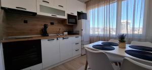 a kitchen with white cabinets and a table with blue pillows at Riverview apartment in Lovech