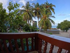 a balcony with a view of the beach and palm trees at Sea view homestay in Dhiggaru