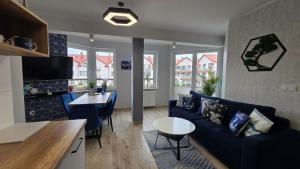 a living room with a blue couch and a table at Apartamenty Hexagon w Darłówku in Darłowo