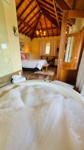 a large bath tub in a room with a bedroom at Chalés Vila do Moinho in Monte Verde