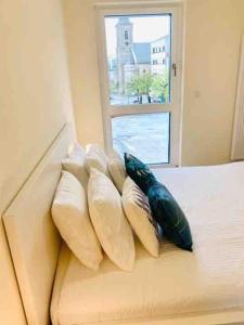 Un grupo de almohadas en una cama con ventana en Luxury Flat in city center with free parking-HOL1, en Luxemburgo