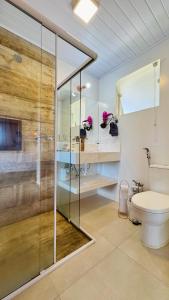 a bathroom with a glass shower and a toilet at Chalés Vila do Moinho in Monte Verde