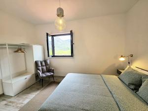 a bedroom with a bed and a chair and a window at Casa Fraga do Suadouro in Campo do Gerês +54 photos