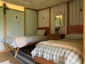 a bedroom with two beds and a mirror at Tregantle Farm Eco GLAMPSITE in Torpoint