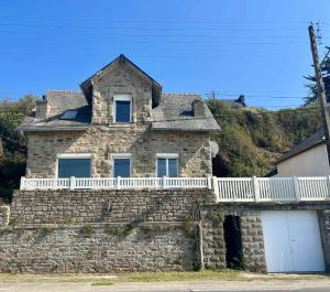 Una casa de piedra con un balcón en la parte superior. en Charming seaside family home - sleeps 8, en Saint-Michel-en-Grève
