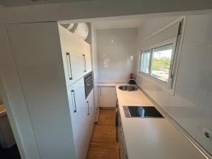 una piccola cucina bianca con lavandino e finestra di Loft cerca de la playa a Punta Umbría
