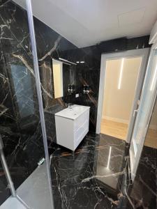 W wyłożonej czarnym marmurem łazience znajduje się umywalka i lustro. w obiekcie Astorga suites w mieście Astorga