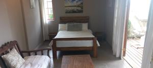 a bedroom with a bed and a table and a balcony at Taylor's Nest in Mancana