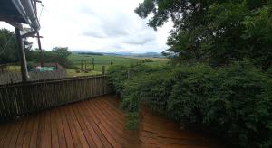 a wooden walkway with a fence and trees at Taylor's Nest in Mancana
