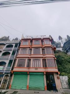 a tall building with green doors and windows at Kinley Homestay in Darjeeling