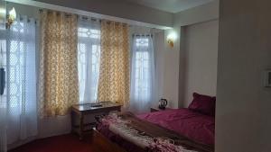 a bedroom with a bed and some windows at Kinley Homestay in Darjeeling +20 photos