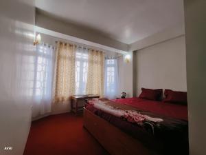 a bedroom with a red bed and windows at Kinley Homestay in Darjeeling