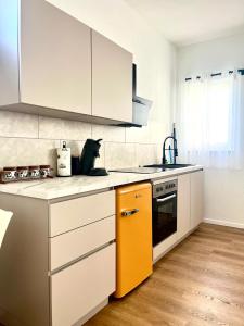 a kitchen with white cabinets and an orange drawer at Studio Apartment Albblick in Trossingen +6 photos