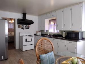 a kitchen with white cabinets and a table with a chair at Sage Street Cottage in Winnsboro