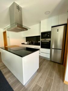 a kitchen with white cabinets and a stainless steel refrigerator at Apartamento Duplex - Beach Apart in Vila Praia de Âncora