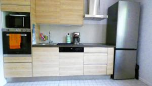 a kitchen with wooden cabinets and a stainless steel refrigerator at Souffle d'air-nature, Plain-pied, Rénové en août in Conflans-Sainte-Honorine