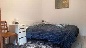 a bedroom with a bed with a blue blanket and a chair at Souffle d'air-nature, Plain-pied, Rénové en août in Conflans-Sainte-Honorine