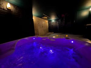 a purple tub in a dark room with lights at Mieuxqualhotel jacuzzi privatif Velvet Desire in Bordeaux