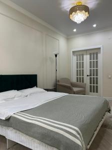 a bedroom with a bed and a chair and a chandelier at AURA on Jumabek street 233 in Bishkek