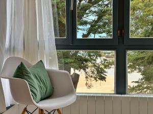 a white chair with a green pillow in front of a window at Maralfrente de Noja- 6020 in Noja