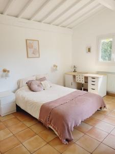 a white bedroom with a bed and a desk at La Saliniere in Roquefort-les-Pins
