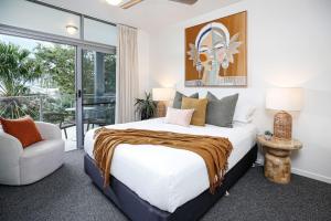 a bedroom with a large bed and a chair at Luxury Cairns Stay with Pool and BBQ in Cairns
