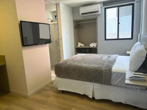 a bedroom with a bed and a flat screen tv at Blue Hotel in João Pessoa