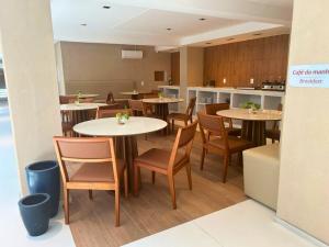 a restaurant with tables and chairs and a kitchen at Blue Hotel in João Pessoa