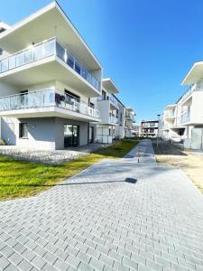 a large white building with a sidewalk in front of it at Apartament Drugi Dom Sztutowo Baltic Twins in Sztutowo