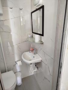 a white bathroom with a sink and a toilet at Stefanos Garden3 in Arménoi