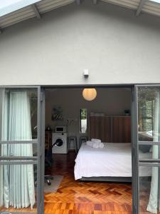 プレトリアにあるApartments on Herbert Bakerのベッドルーム1室(ベッド1台付)、ガラスのスライドドアが備わります。
